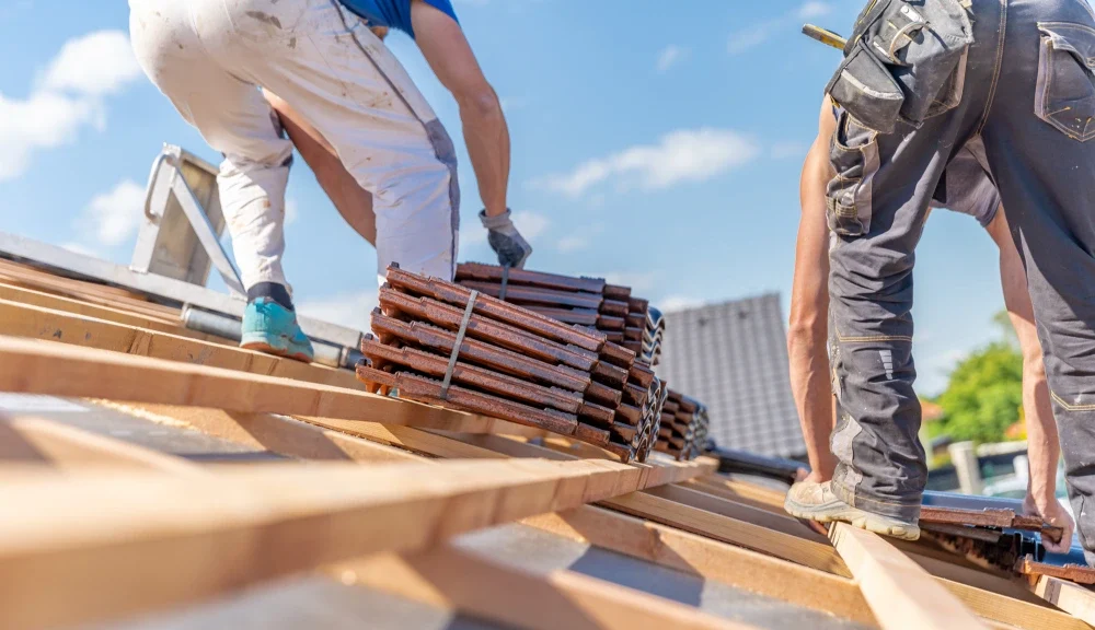 residential roofers standing on a house's roof structure, installing roof shingles