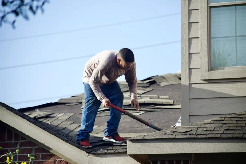 roofing contractor standing on top of the roof to replace its damaged parts